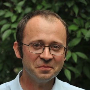 Portret mężczyzny w okularach przed zieloną ścianą z bluszczem