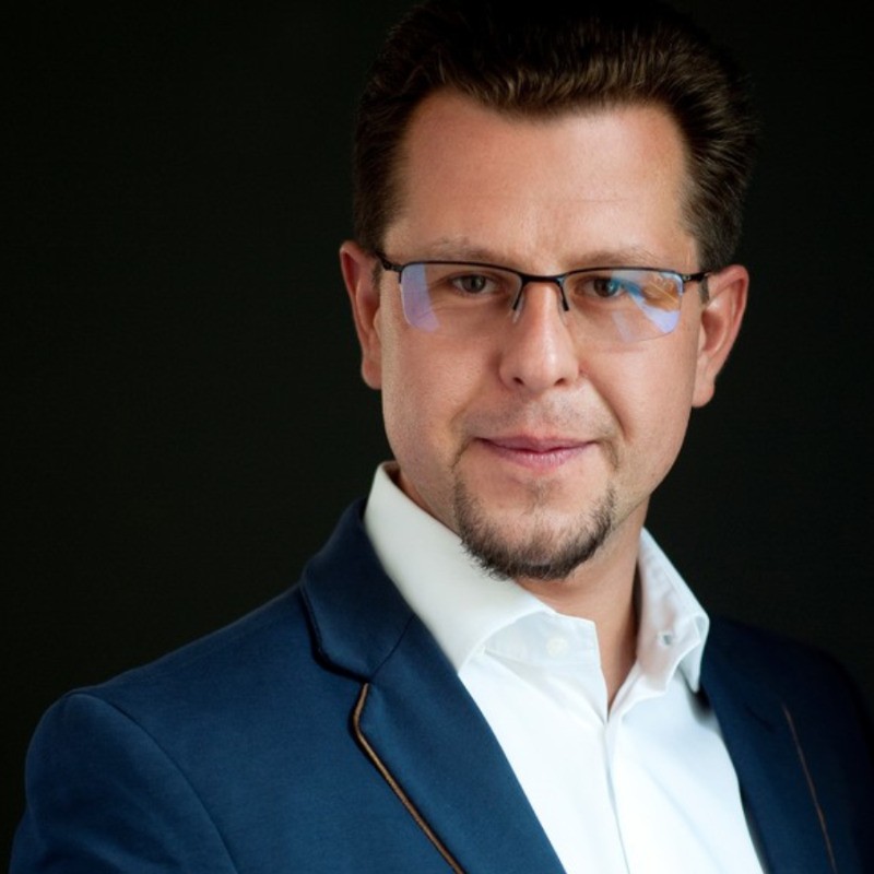 Portret profesjonalnego mężczyzny w okularach i granatowej marynarce na ciemnym tle