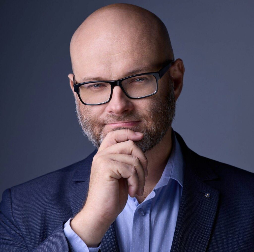 Łysy mężczyzna w okularach i garniturze, myślący, profesjonalny portret biznesowy.