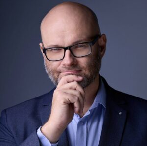 Łysy mężczyzna w okularach i garniturze, myślący, profesjonalny portret biznesowy.