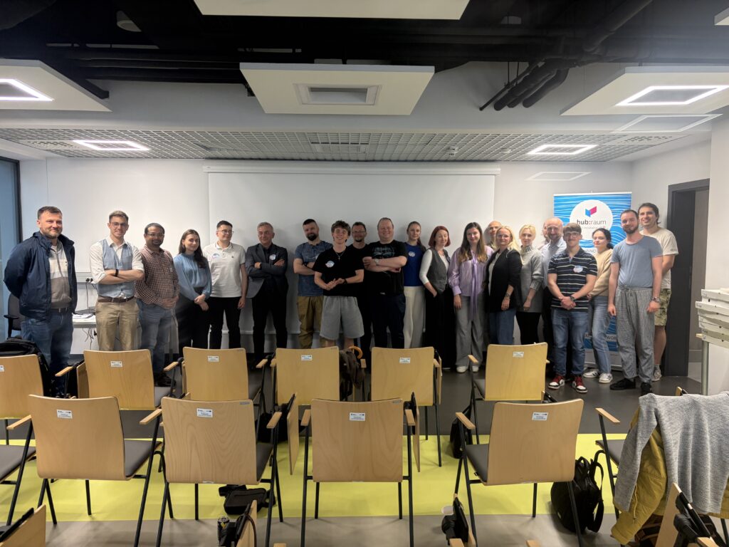 Grupa pracowników hubRaum stojąca w sali konferencyjnej podczas zespołowego spotkania firmowego.